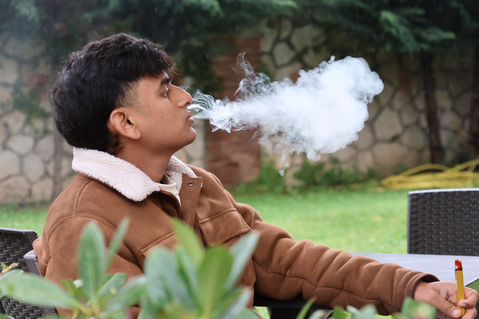 Candid moment, exhaling smoke in the garden