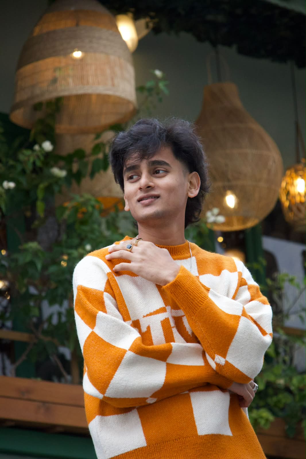 Portrait in checkered knit under rattan lanterns