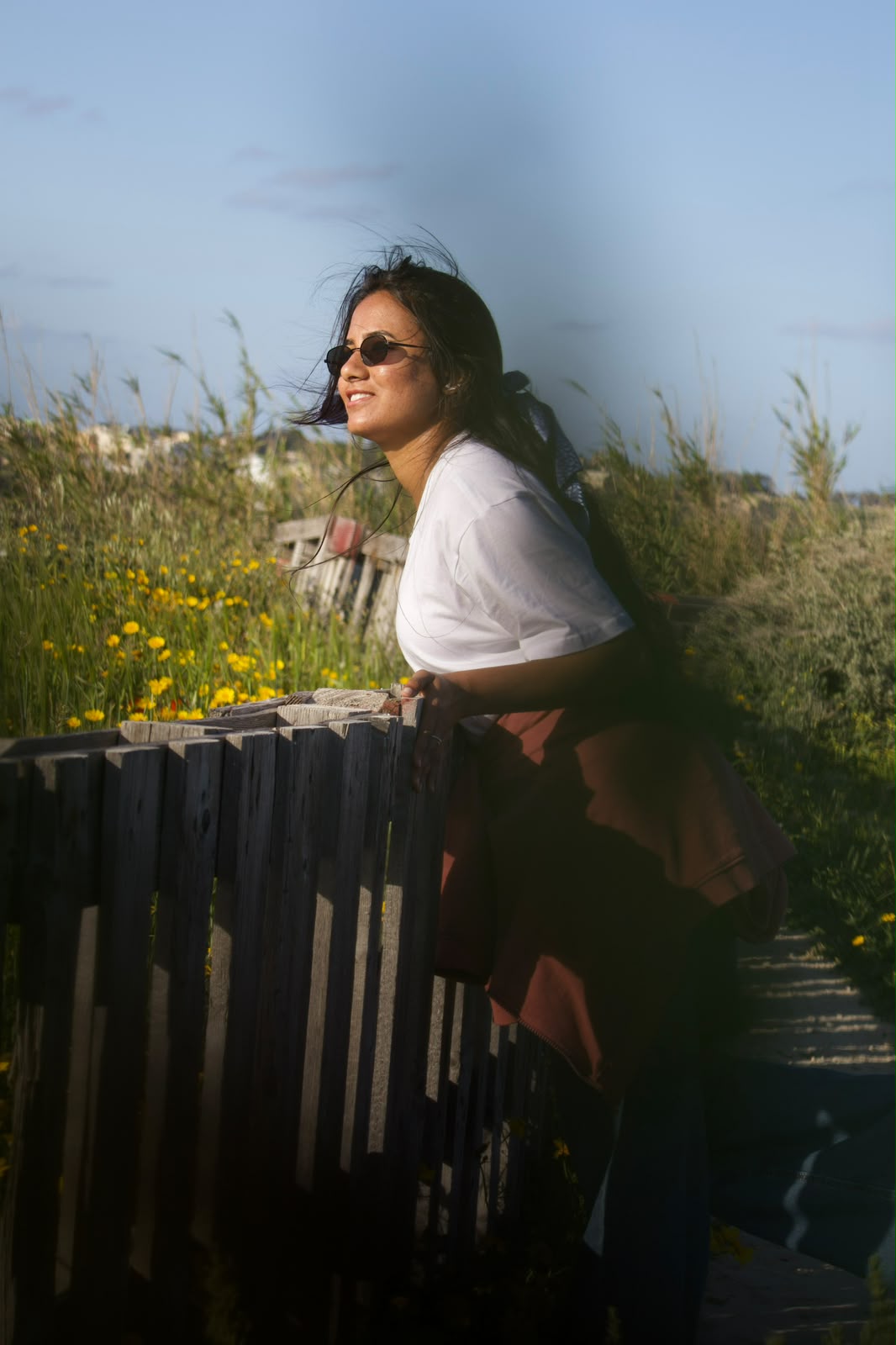 Side profile portrait by a wooden fence at sunset