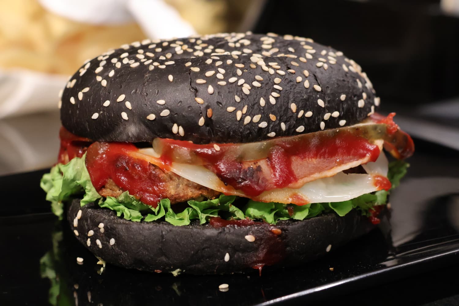 Charcoal bun burger plated in moody light